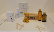 An array of bikini waxing kit products from Once, including a small wax warmer, boxes of wax, pre and post depilatory cleanser lotion, medium spatulas, facial sticks, and cornstarch powder.